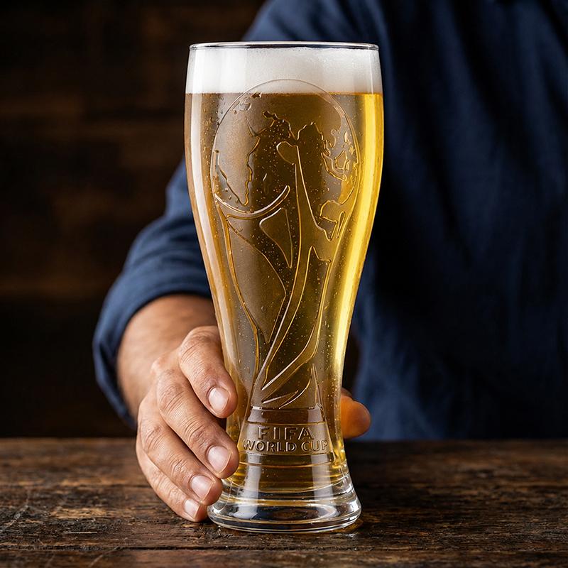 Hand holding FIFA World Cup trophy embossed pilsner beer glass