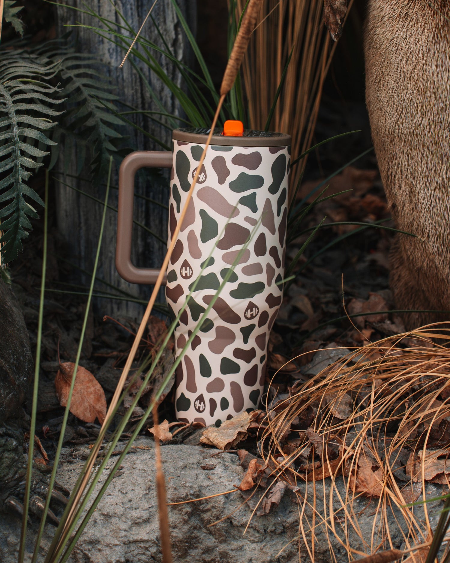 Duck Camo Traveler in nature — ferns, pine straw, outdoor lifestyle